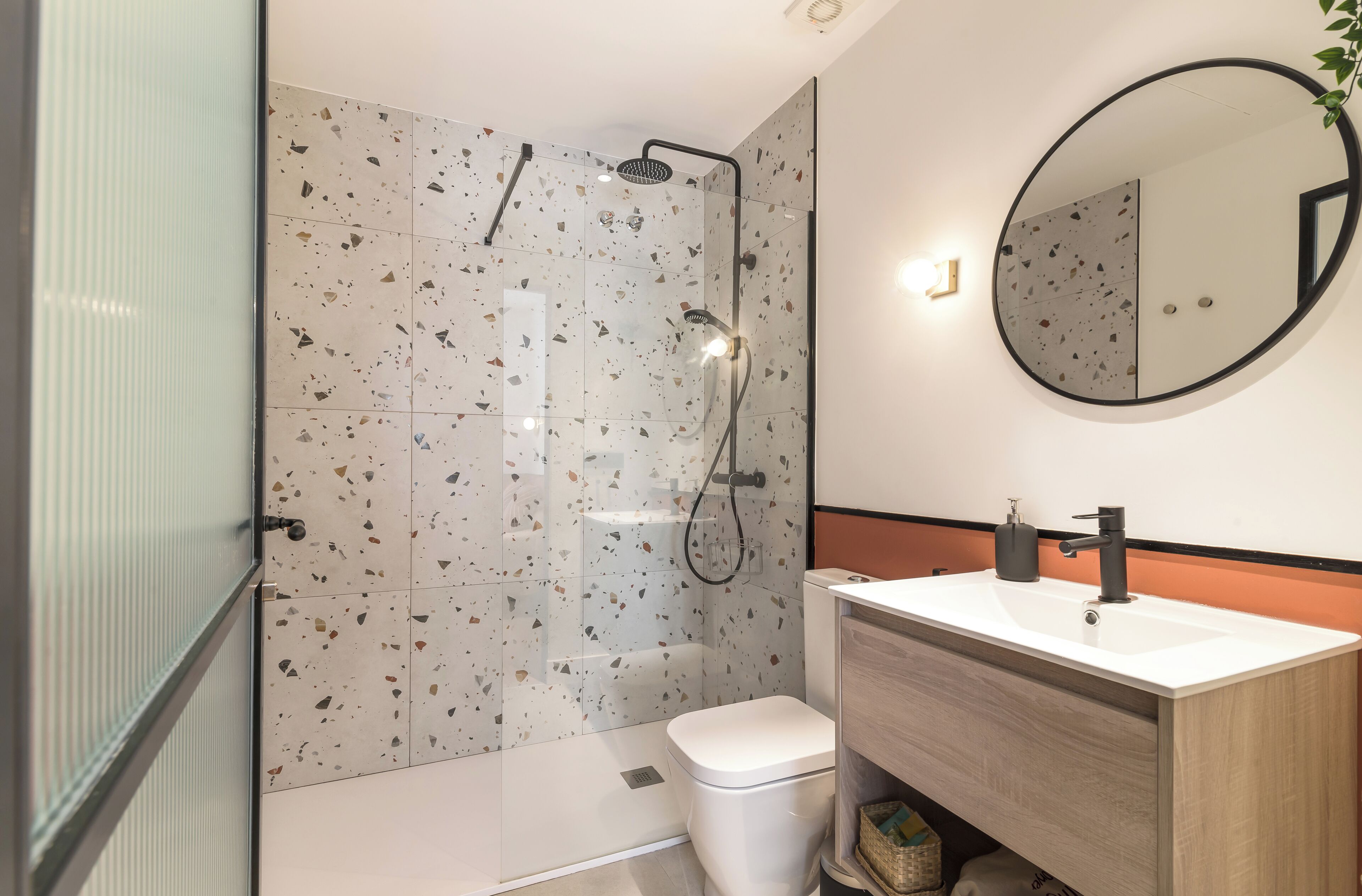 A modern bathroom with a shower, toilet, and sink.