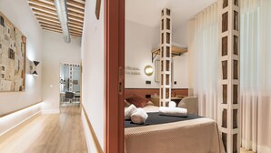 A hotel room with a bed, a wooden ladder, a mirror, and a wall with a light fixture. - Cálamo Guesthouse (Madrid)