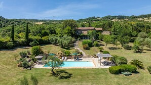 Ein Haus mit Swimmingpool, umgeben von üppiger Vegetation und einem Kiesweg, der zum Eingang führt.