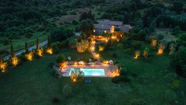 Ein großes Haus mit Swimmingpool, umgeben von einem gut beleuchteten Garten und einem Steinweg, der zum Eingang führt.