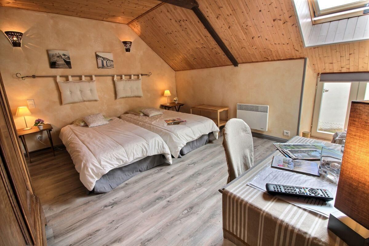 Une chambre avec deux lits, un bureau avec une chaise, une lampe et une fenêtre.