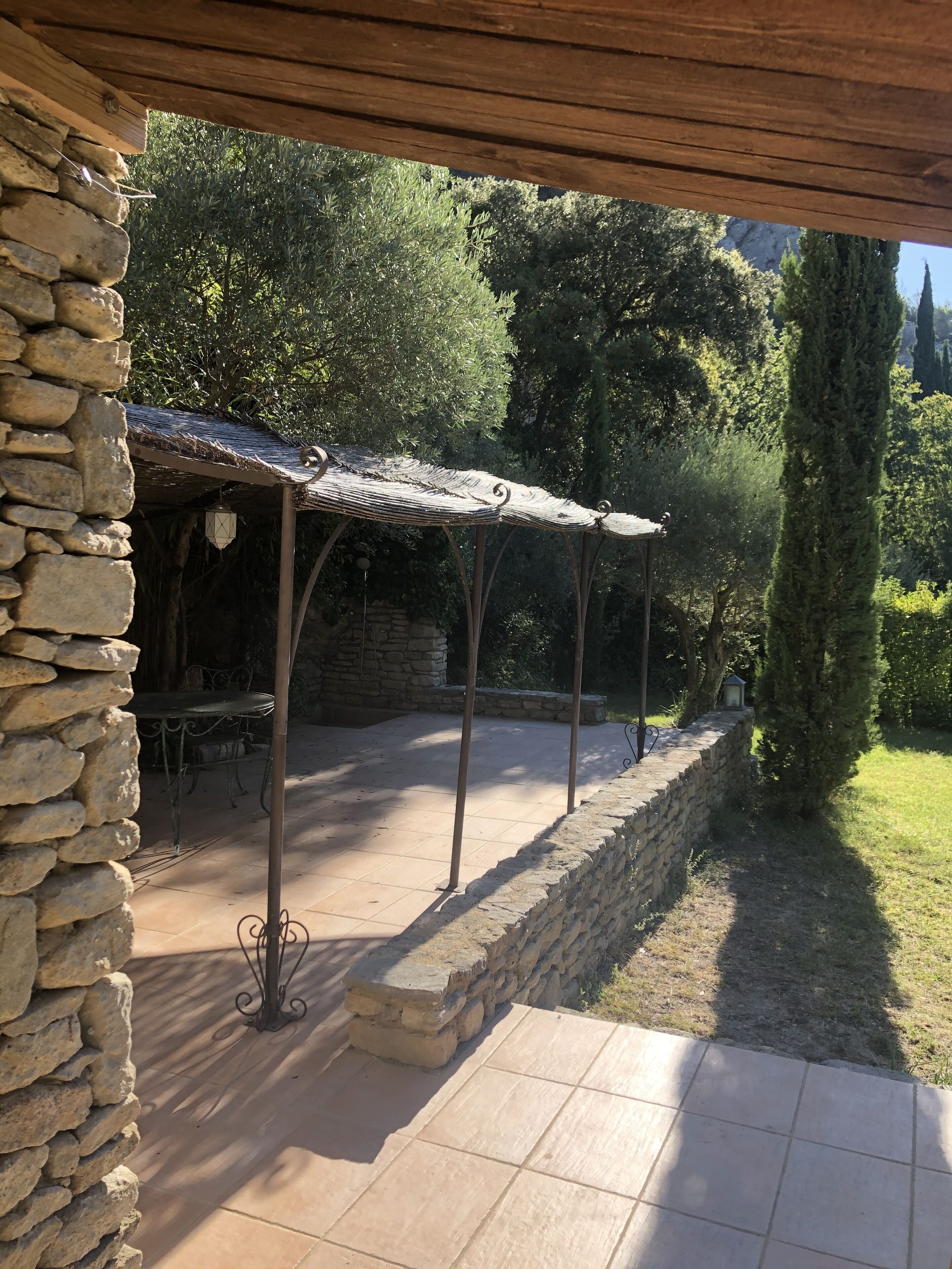 Un muro de piedra, un patio cubierto con suelo de baldosas y un banco de piedra.