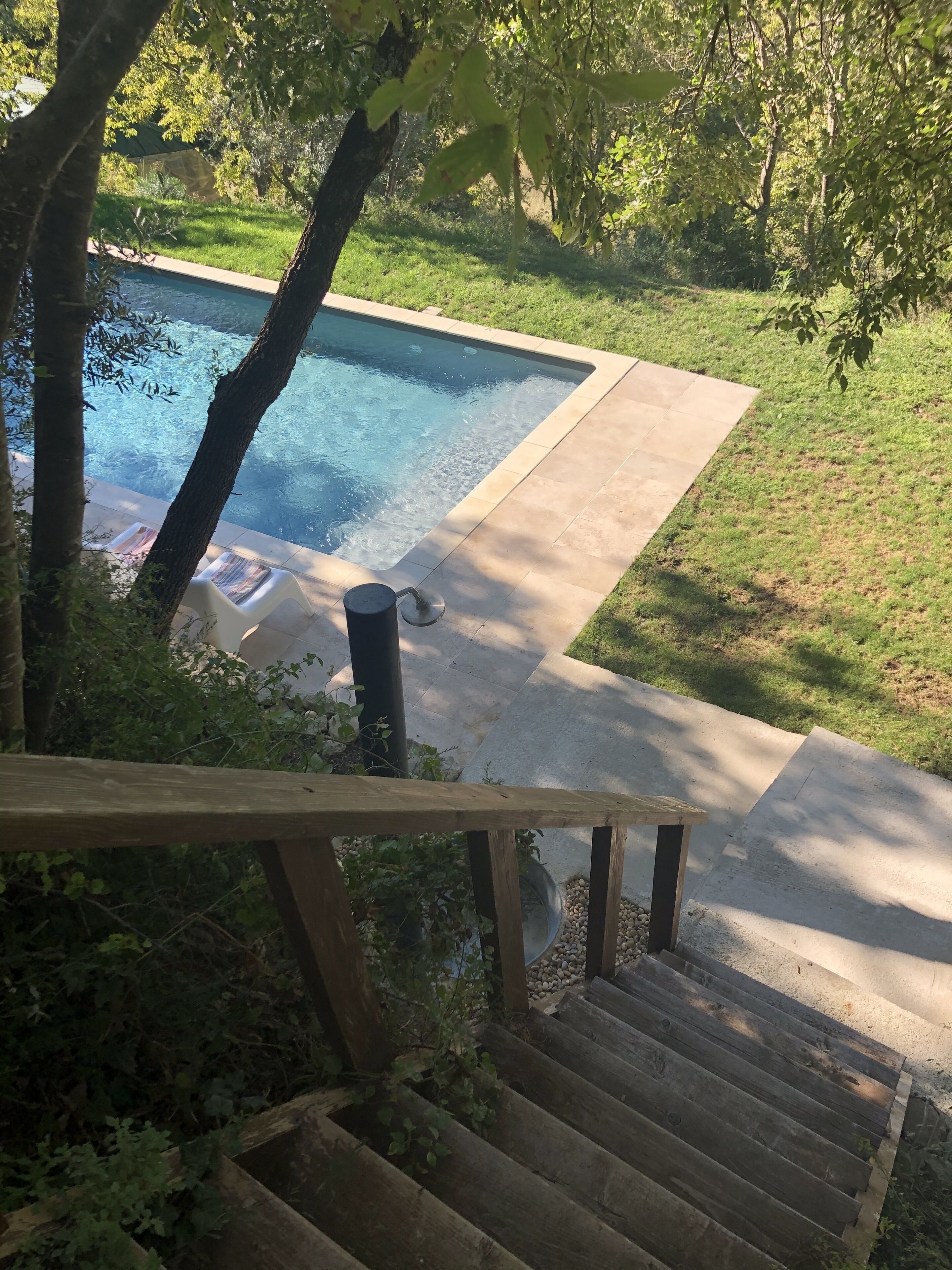 Une piscine avec une terrasse en bois et un escalier menant à l’eau.