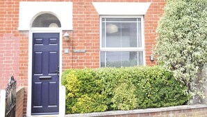 A two-story brick house with a dark blue front door, a small front garden, and a chimney. - Little Lane is a charming, recently refurbished 2 bedroom cottage sleeping 4 (Gosport)