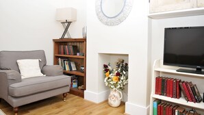 A living room with a grey sofa, a bookshelf, a TV, and a fireplace. - Little Lane is a charming, recently refurbished 2 bedroom cottage sleeping 4 (Gosport)
