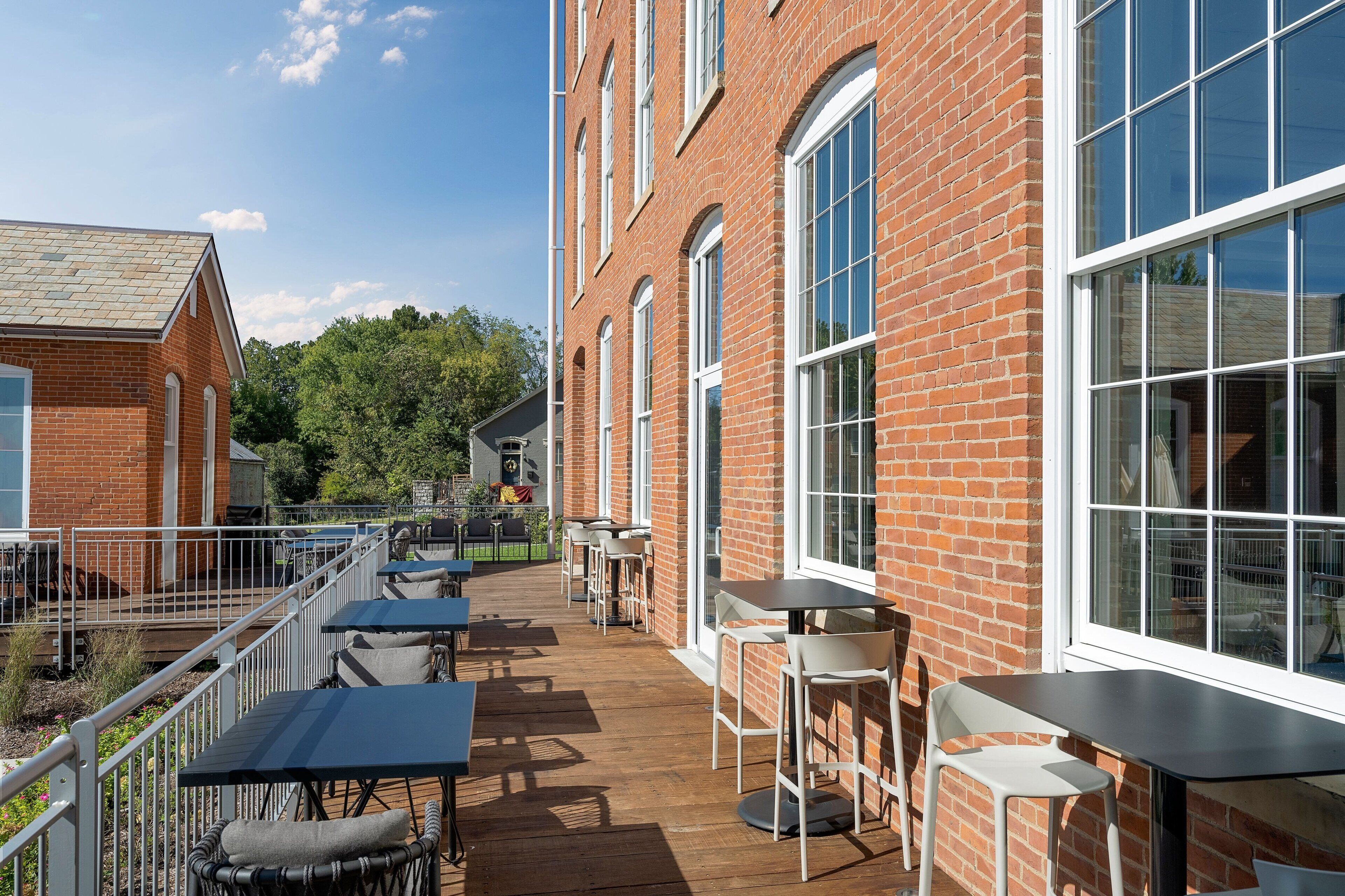 A brick building with large windows and outdoor seating.
