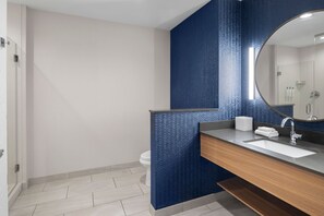 A modern bathroom with a large mirror, a wooden vanity, and a white sink.