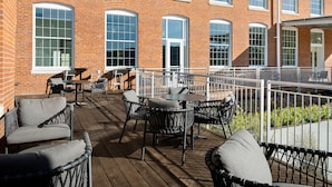 A covered outdoor seating area with wicker furniture and a brick building in the background. - Fairfield Inn & Suites Madison Historic Eagle Cotton Mill (Madison)