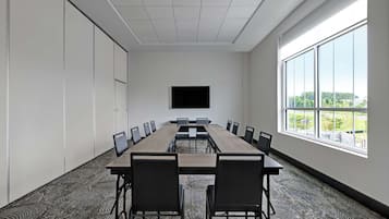 Ein Konferenzraum mit einem langen Tisch, Stühlen, einem Flachbildfernseher und großen Fenstern mit Blick.
