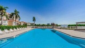 Une piscine avec des chaises longues, des palmiers et une vue sur la mer.