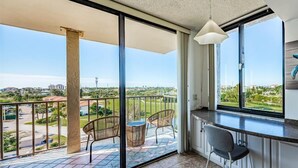 Un balcon donnant sur un quartier résidentiel, un coin repas avec une chaise et un luminaire suspendu.