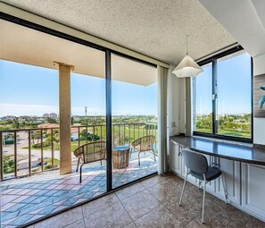 Un balcon donnant sur un quartier résidentiel, un coin repas avec une chaise et un luminaire suspendu.