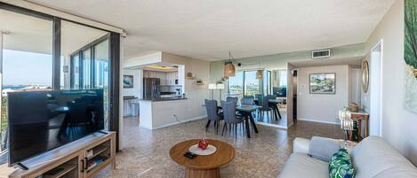 A modern living room with a TV, sofa, coffee table, and dining area.