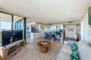 Una sala de estar moderna con televisor, sofá, mesa de centro y comedor.
