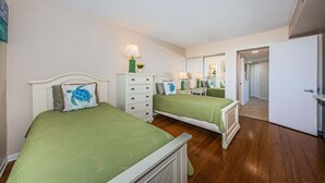 Une chambre avec deux lits, une commode et un miroir.