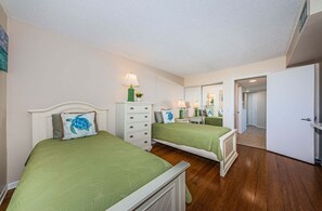 Une chambre avec deux lits, une commode et un miroir.