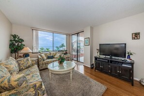 Un salon avec un canapé, une table basse, un téléviseur et une vue sur l’extérieur.