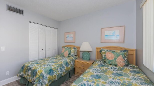 A bedroom with two beds, a nightstand, a lamp, and a window. - 2BR condo with golf course views, pool, hot tub, and balcony. (St. Petersburg)