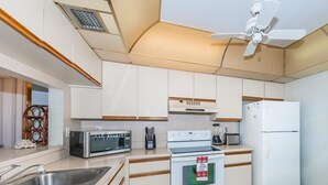 A modern kitchen with white cabinets, stainless steel appliances, and a wooden floor. - 2BR condo with golf course views, pool, hot tub, and balcony. (St. Petersburg)