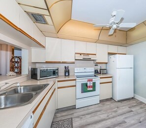 Een moderne keuken met witte kastjes, roestvrijstalen apparatuur en een houten vloer.