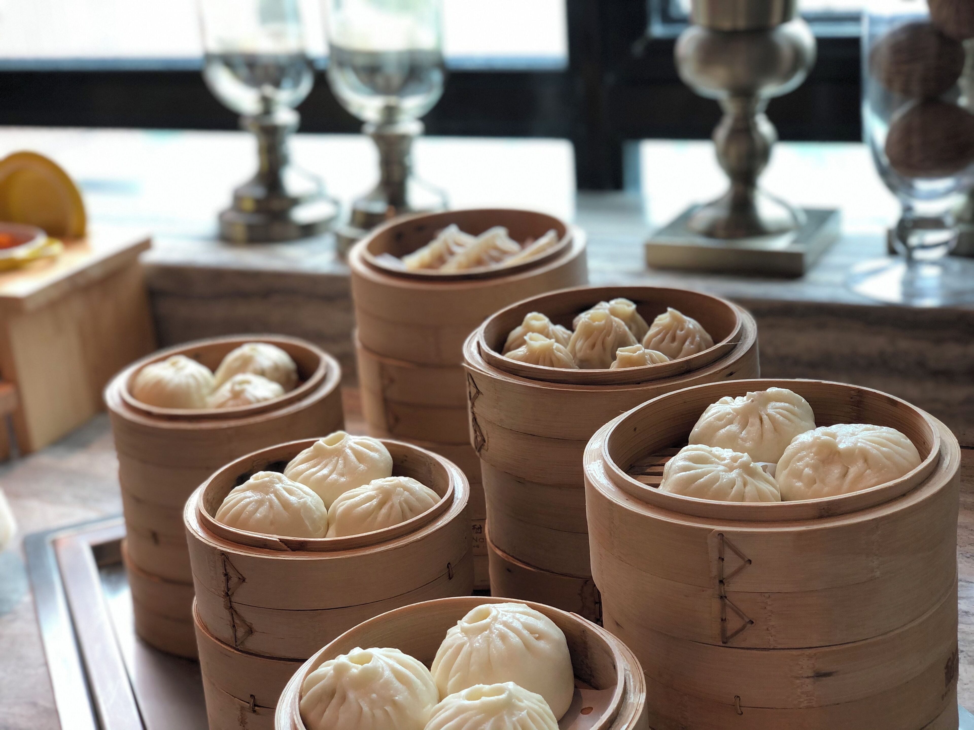 A table with several bamboo steamers containing white dumplings.