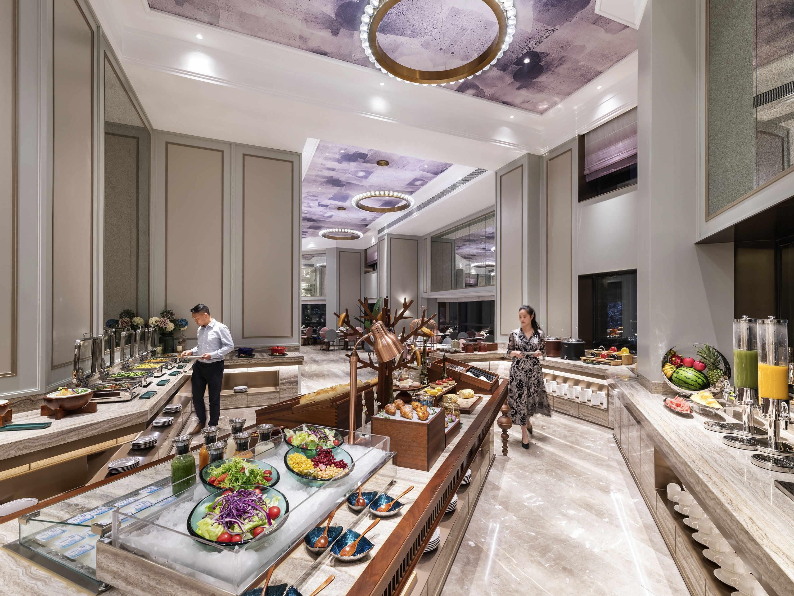 Un amplio vestíbulo de hotel con zona de buffet, mostrador de recepción y un techo decorativo.