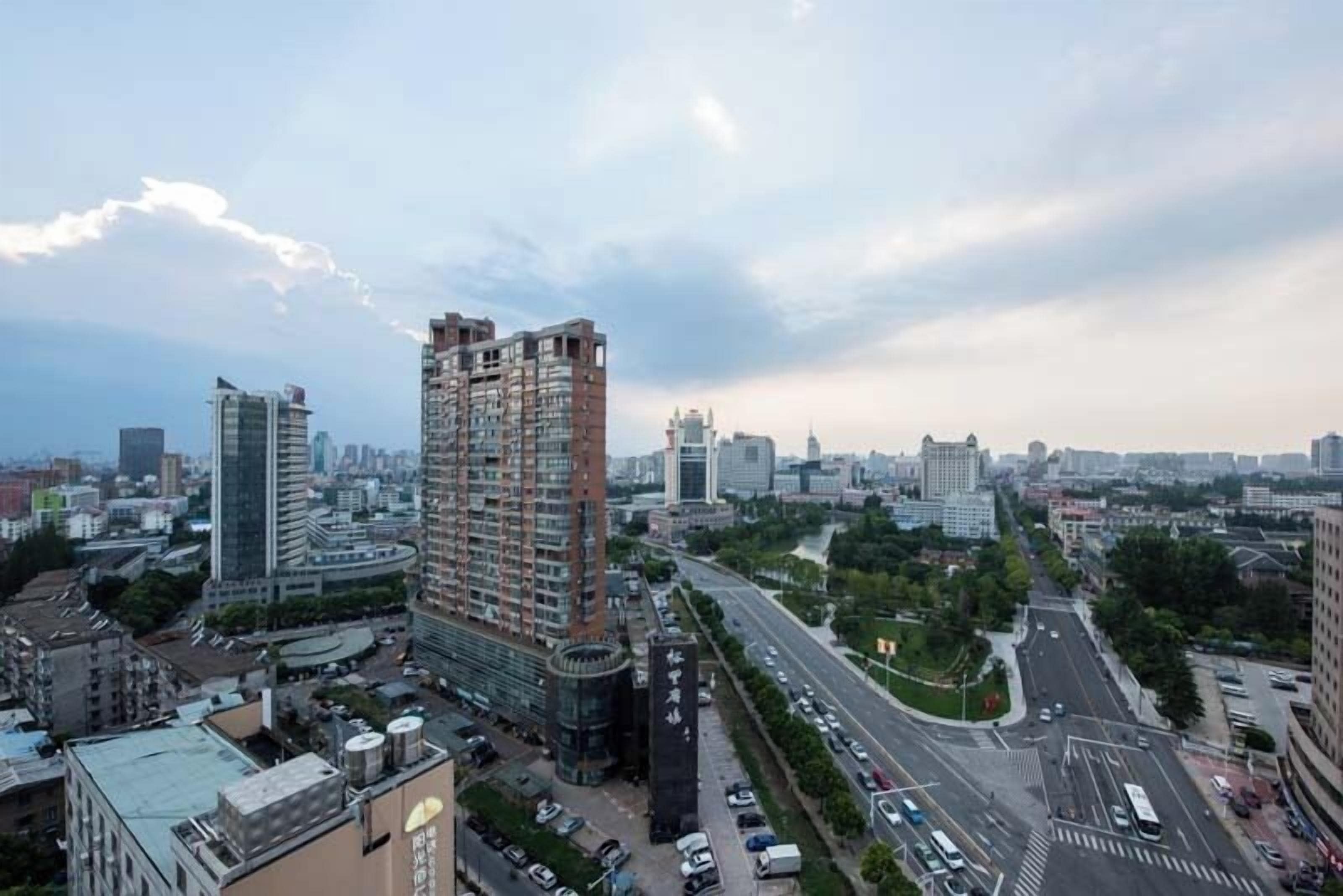 A high-rise building with multiple floors, surrounded by other buildings and a busy road with vehicles.