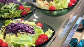 A buffet with various salads and fruits.