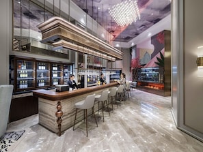 Un'area bar con pavimento in marmo, un bancone in legno e un barista.