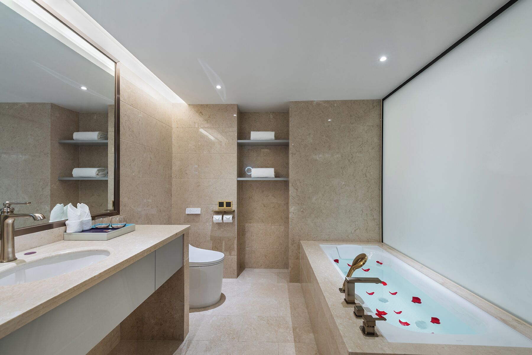 A modern bathroom with a large bathtub, a vanity with a mirror, and shelves with towels.