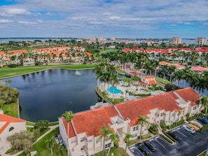 Un quartiere residenziale con un ampio specchio d'acqua, edifici con tetti rossi e un campo da golf.