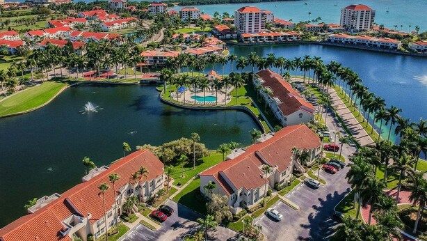 Un resort con varias edificaciones, una fuente central y un puerto deportivo.