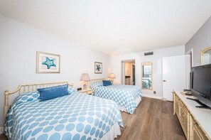 A bedroom with two beds, a television, and a dresser.