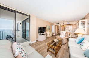 A spacious living area with a balcony, a dining area, and a kitchen.