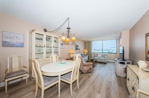 A living room with a dining area, a television, and a view of the city.
