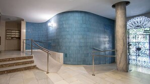 A curved blue-tiled wall, a marble staircase with metal railings, and a decorative metal gate. - Jardines de Candelaria Cadiz (Cádiz)
