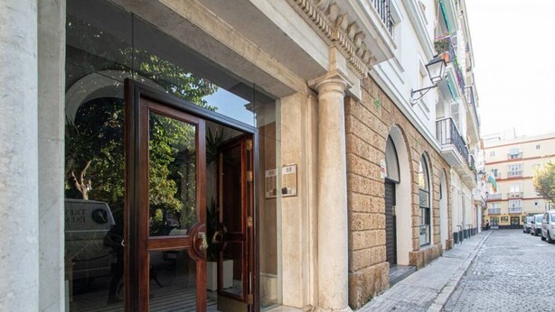 A hotel entrance with a wooden door and a stone facade. - Jardines de Candelaria Cadiz (Cádiz)