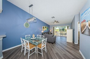 A modern living room with a glass dining table, grey sofa, and a ceiling fan. - VVW 6-236 - Vista Verde West - Premium (St. Petersburg)