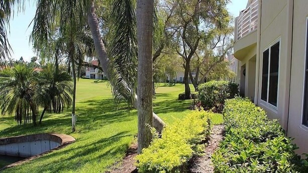 A well-maintained lawn with a variety of trees and shrubs, a small pond, and a building with large windows. - VVW 6-138 - Vista Verde West - Standard (St Petersburg)