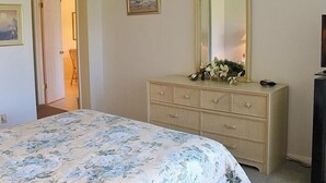 A bedroom with a bed, a dresser, a mirror, and a door leading to another room. - VVW 6-138 - Vista Verde West - Standard (St Petersburg)