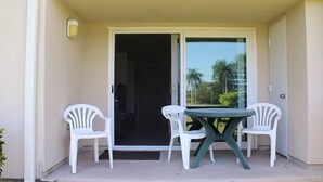 A balcony with a table and two chairs, a sliding glass door, and a light fixture. - VVW 6-138 - Vista Verde West - Standard (St Petersburg)