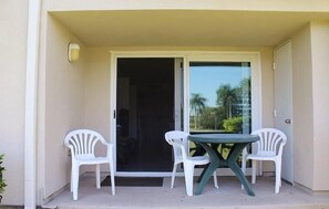 Een balkon met een tafel, twee stoelen, een schuifpui en een lamp.