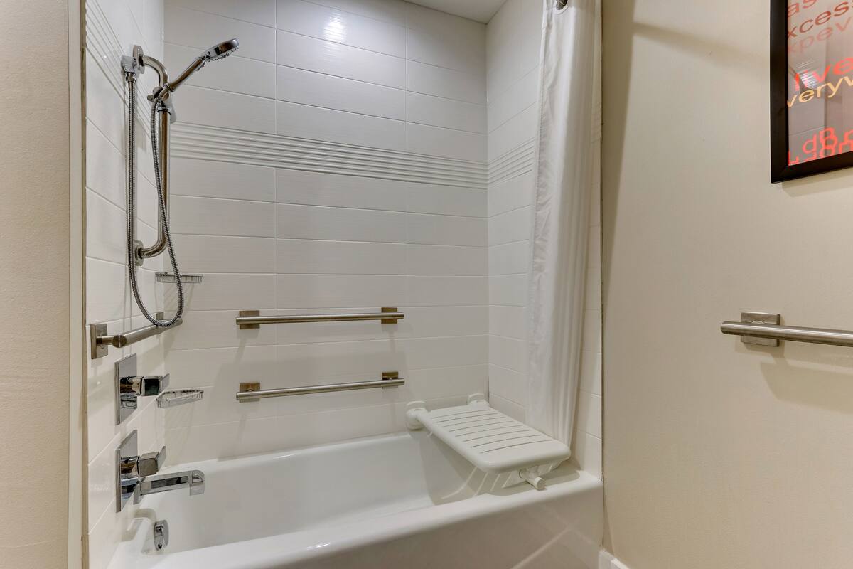 Une salle de bain moderne équipée d’une baignoire, d’une douche et de barres d’appui.