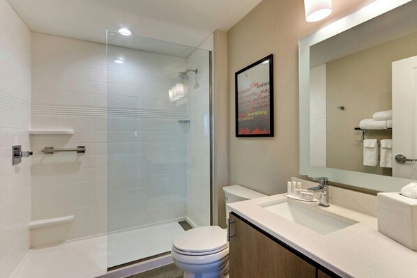 A modern bathroom with a glass-enclosed shower, a toilet, a sink, and a mirror.