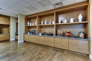 Uma cozinha moderna com armários de madeira, bancada com diversos eletrodomésticos e objetos decorativos.