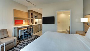 Ein Hotelzimmer mit Bett, Schreibtisch, Stuhl, Fernseher, Mikrowelle, Kaffeemaschine und Duschbereich.