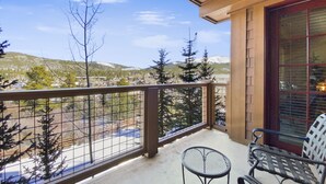 Un balcon avec une balustrade en métal, deux chaises en métal et une petite table ronde.