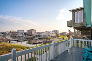 A waterfront property with a dock, a flag, and a view of houses across the water.