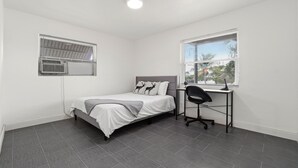 A bedroom with a bed, a desk, and a window. - Luxury Beach Condo Getaway with fast Wifi (Lake Worth)