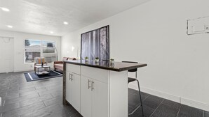 A modern kitchen with white cabinets, a black countertop, and a large window. - Luxury Beach Condo Getaway with fast Wifi (Lake Worth)